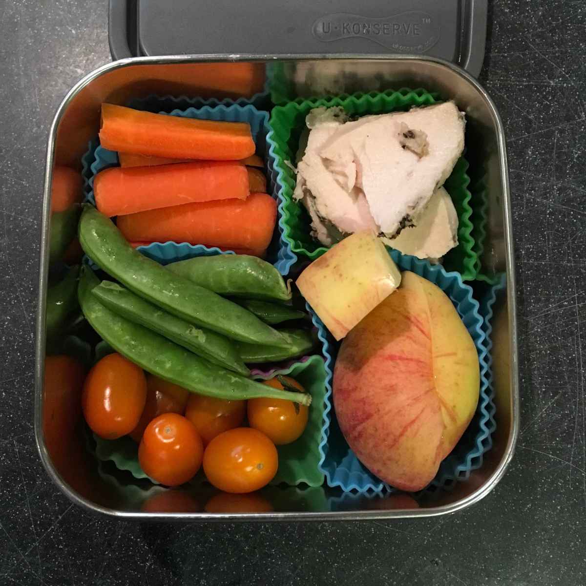 Veggies, fruit, and meat separated in U Konserve square steel dish using silicone cups