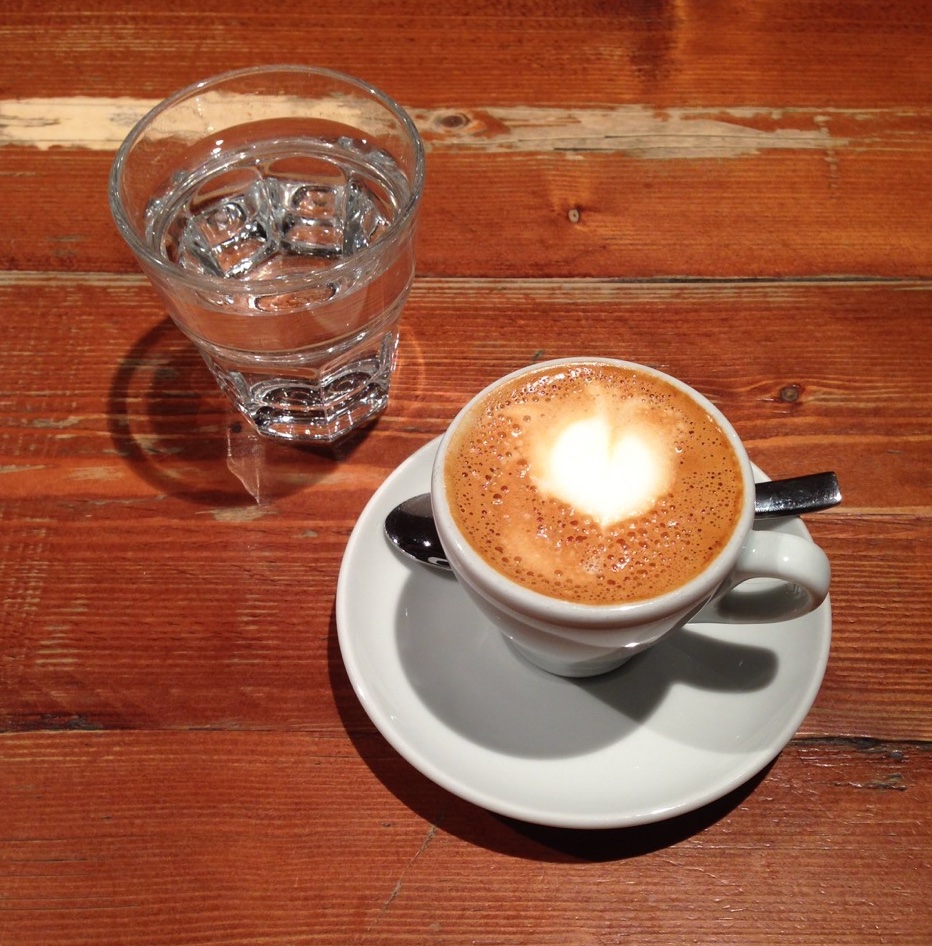 espresso with foam art served with sparkling water