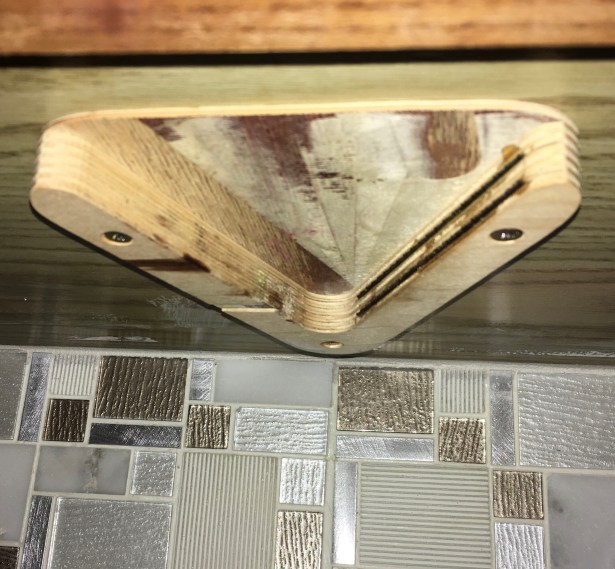 V shaped wooden jar opener screwed to bottom of upper cabinet