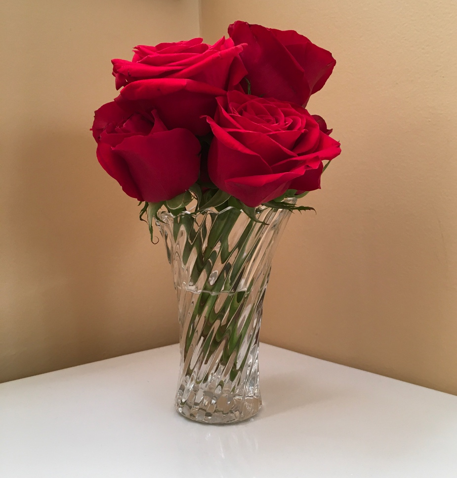 Half a dozen red roses in a small crystal vase