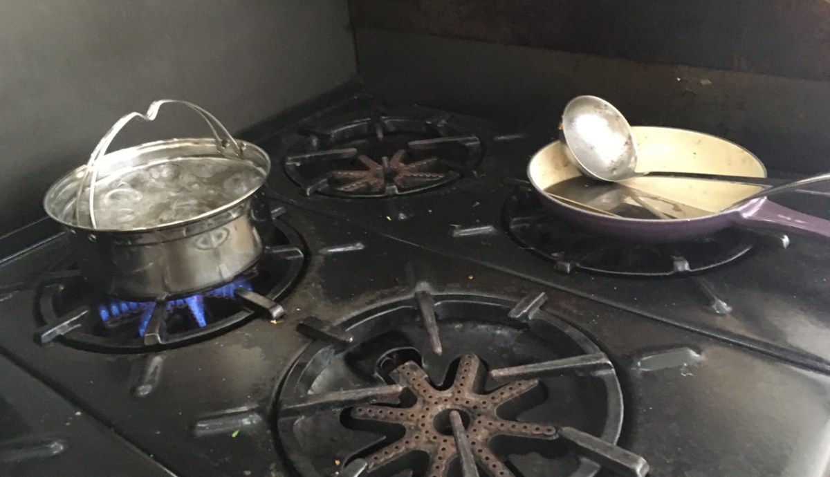 Saratoga Jack secondary cook pot boilding water on messy stove top next to used fry pan