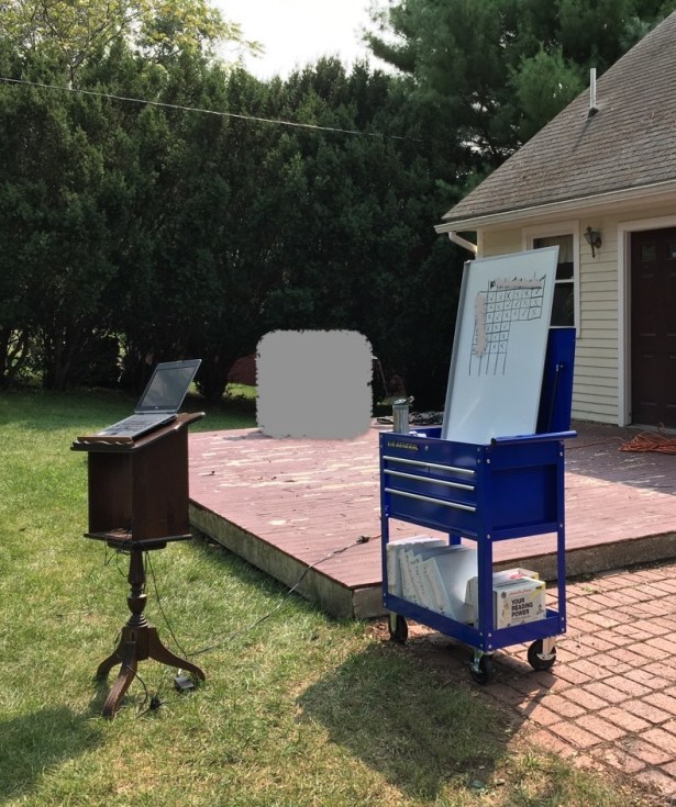 Lectern with laptop and whiteboard propped on mobile tool cart outside