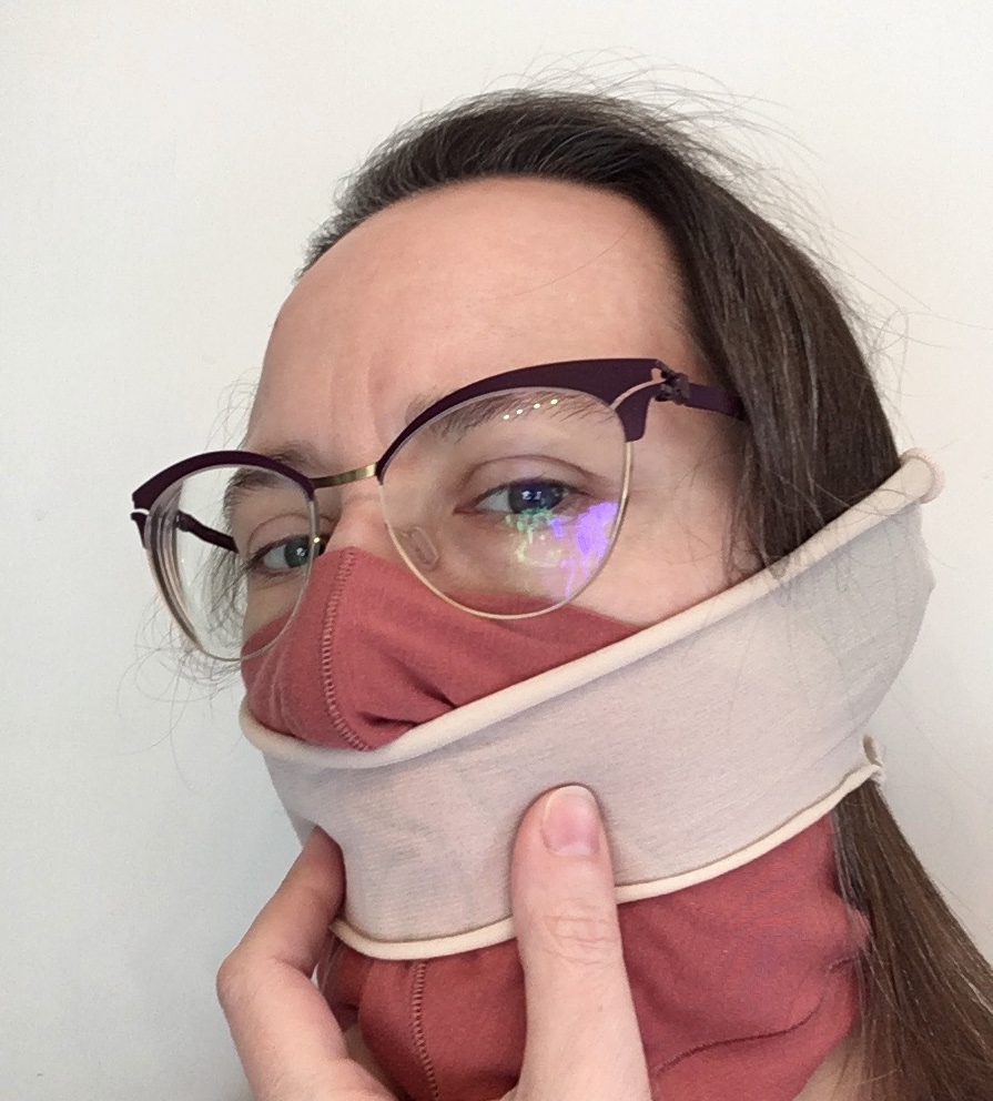 Woman with nylon tube over cotton mask making it fit tighter