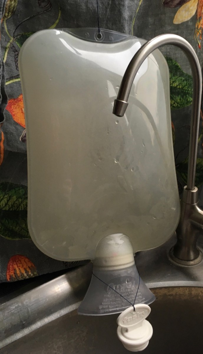 Fashy hot water bottle hanging upside down with cap off to drip dry over sink