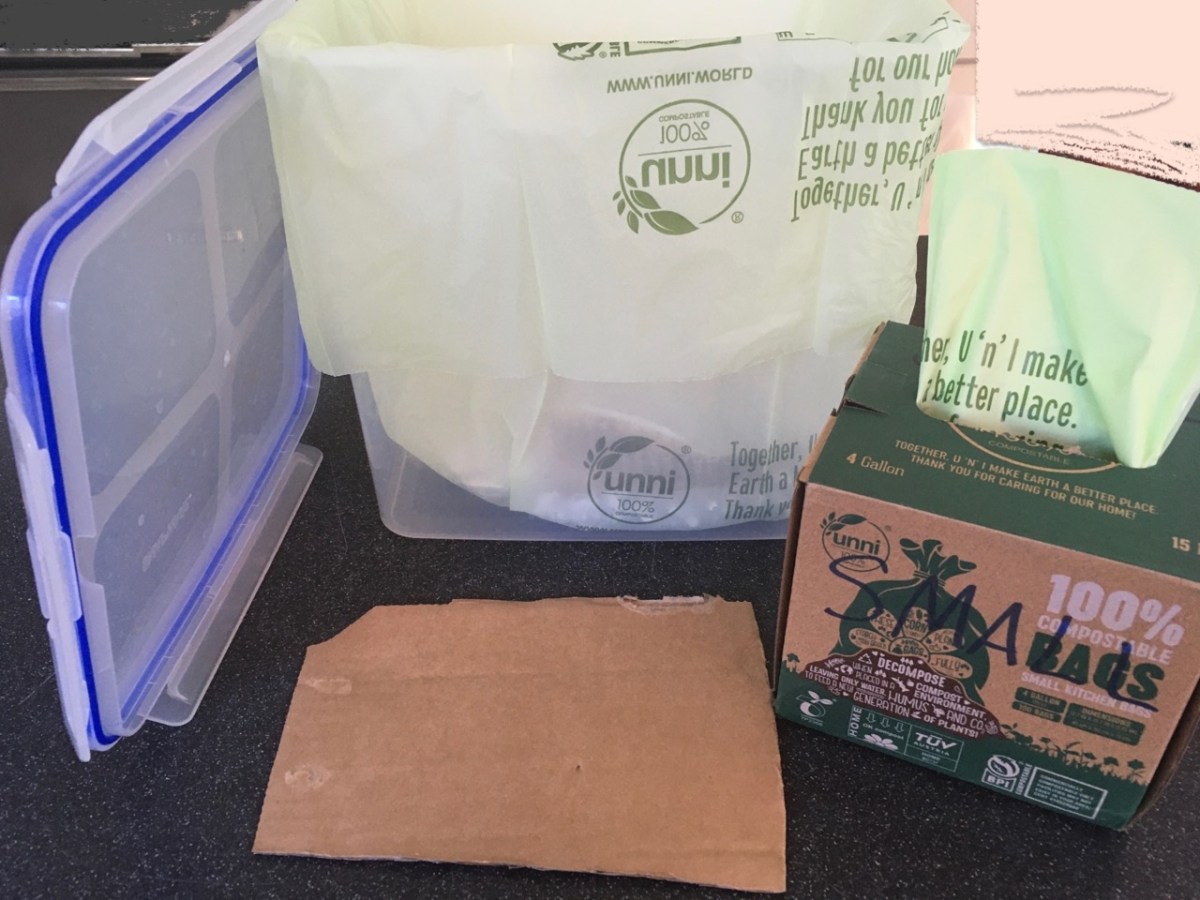Snapware food storage bin and lid lined with UNNI compostable bag with cardboard scrap nearby