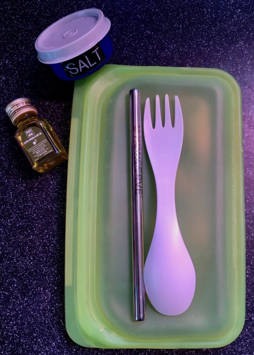 Stasher green silicone snack bag with spork, stainless straw, mini olive oil bottle and tiny dish of salt ready to fit inside