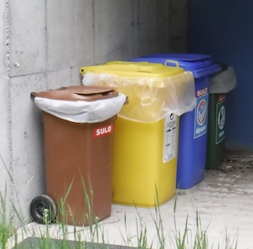 brown compost bin, yellow trash barrel, and blue and green recycling bins for curbside collection