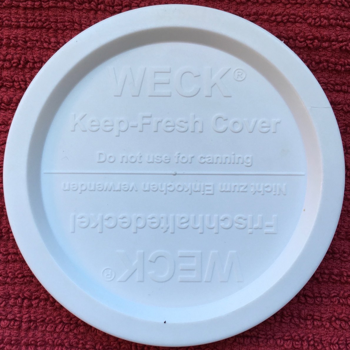 Weck canning jar lid in plastic, top view, reminds user not to use freshness cover for canning