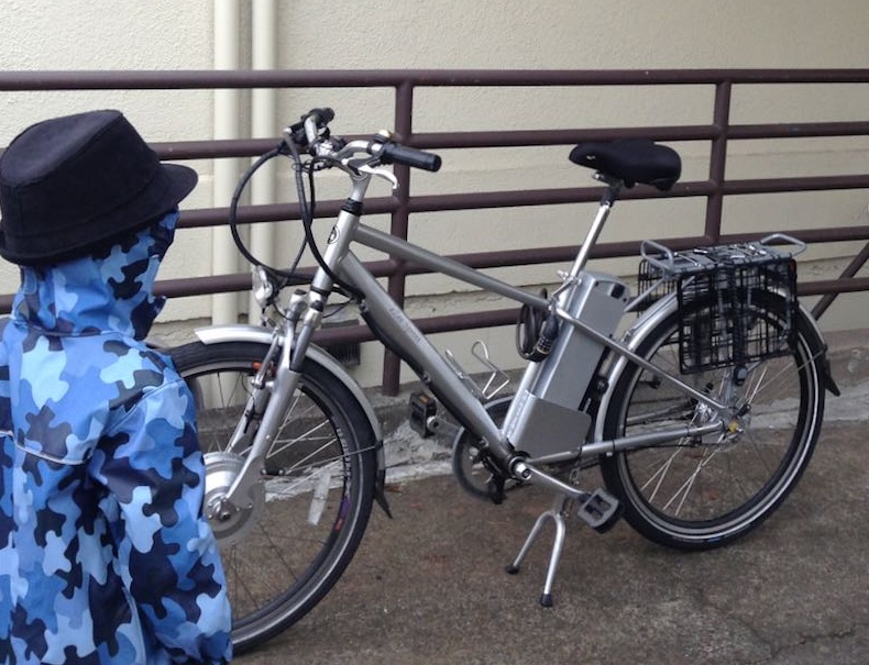 child standing next to silver e-bike