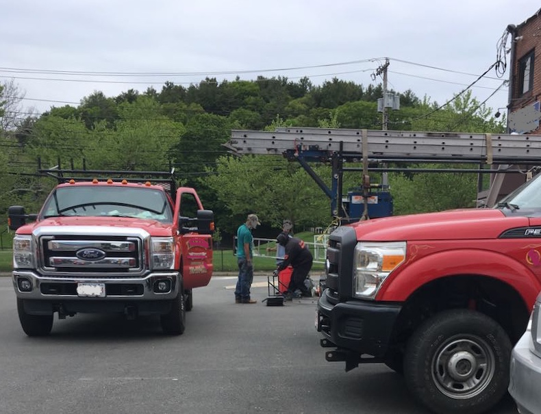 commercial trucks alongside men working with equipment