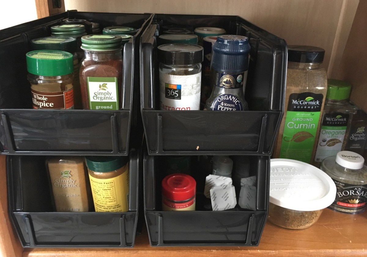Wooden shelf with 4 AkroBins holding assorted spice jars with larger containers alongside