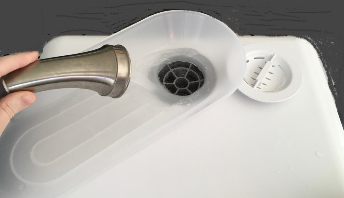 Water flowing from pull out spray head into dishwasher filling hold