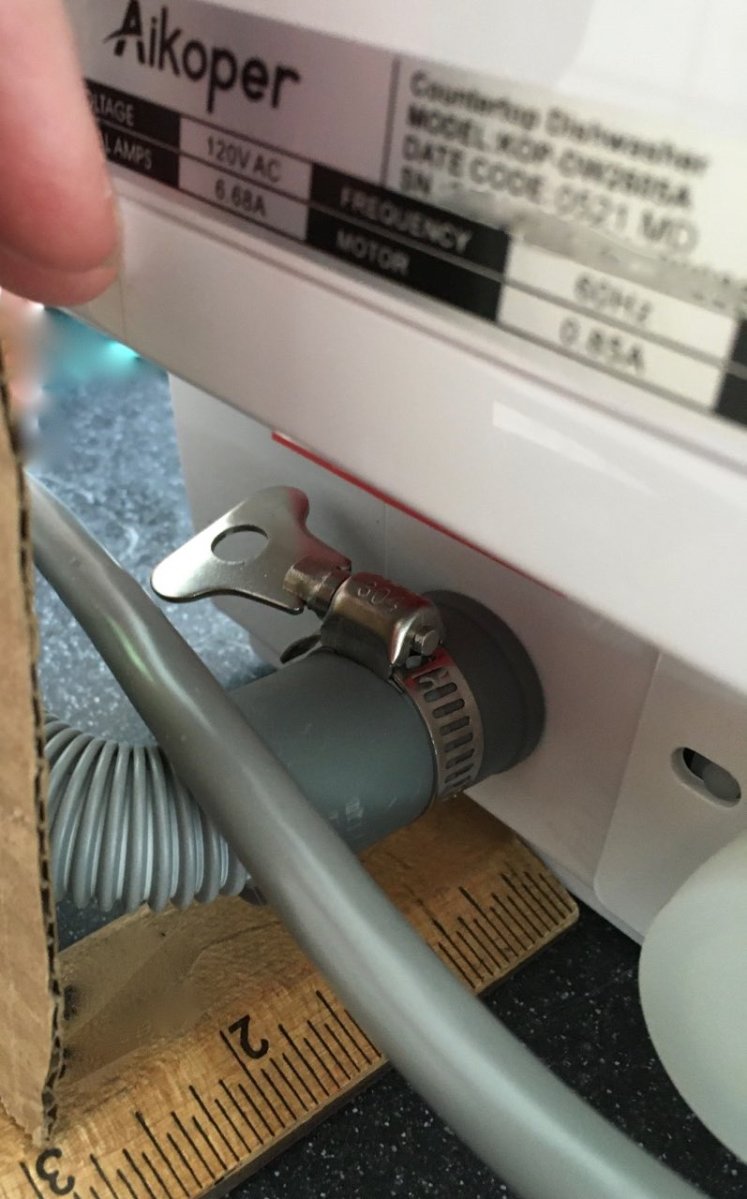 Ruler and cardboard showing gap between back of appliance and bent drain hose as if pushed back against a wall