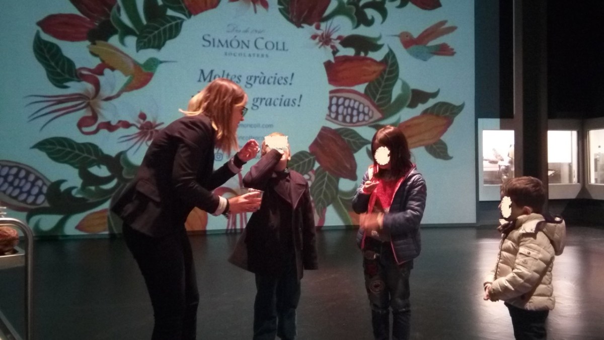 Tour leader at Simón Coll offering bitter unsweetened chocolate to 3 child volunteers