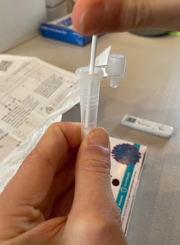 Fingers squeezing plastic test tube for COVID test