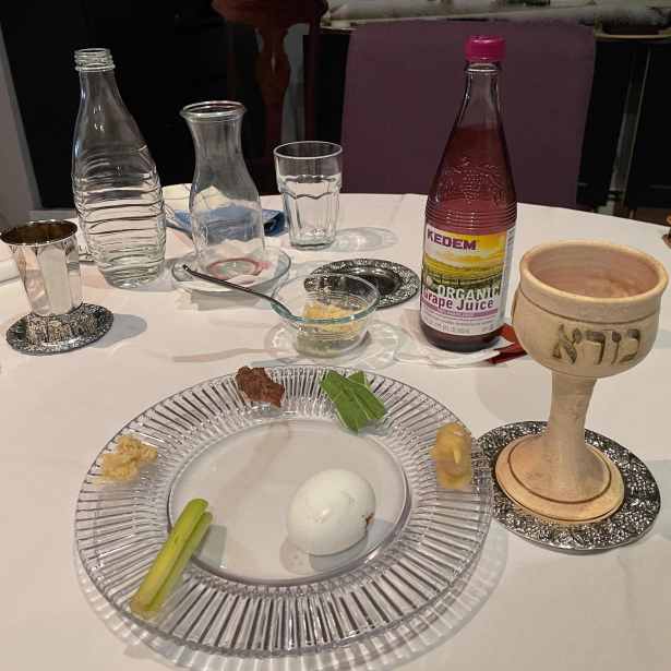 Table after meal with seder plate containing maror, vegetables, charoset, egg, etc