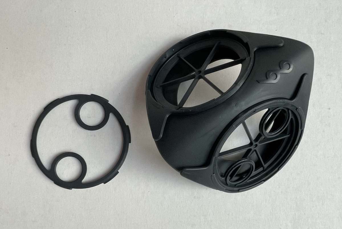 Ergonomic face piece with one filter cap on and the other removed