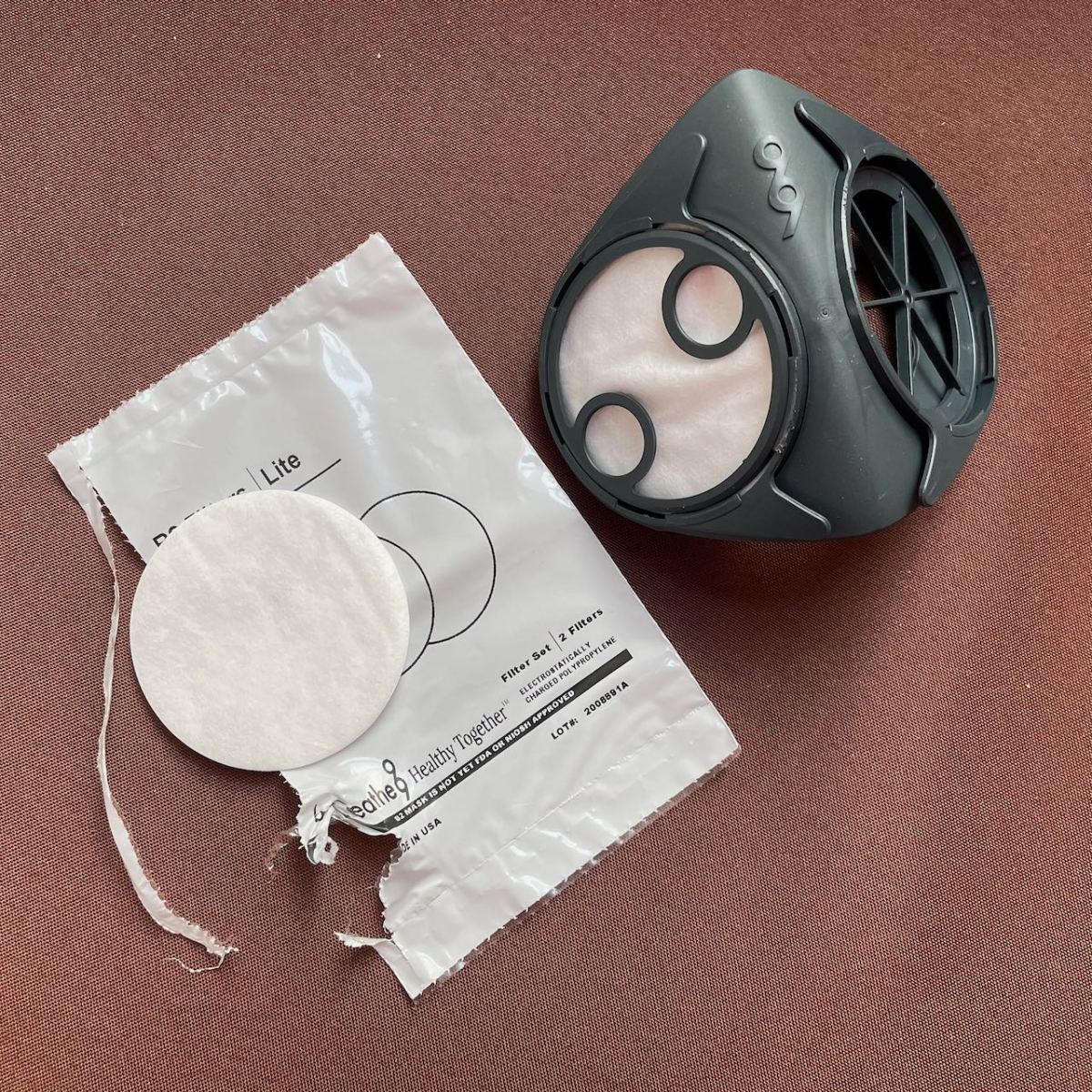 Ergonomic face piece with one filter installed and capped while the second filter is still on table