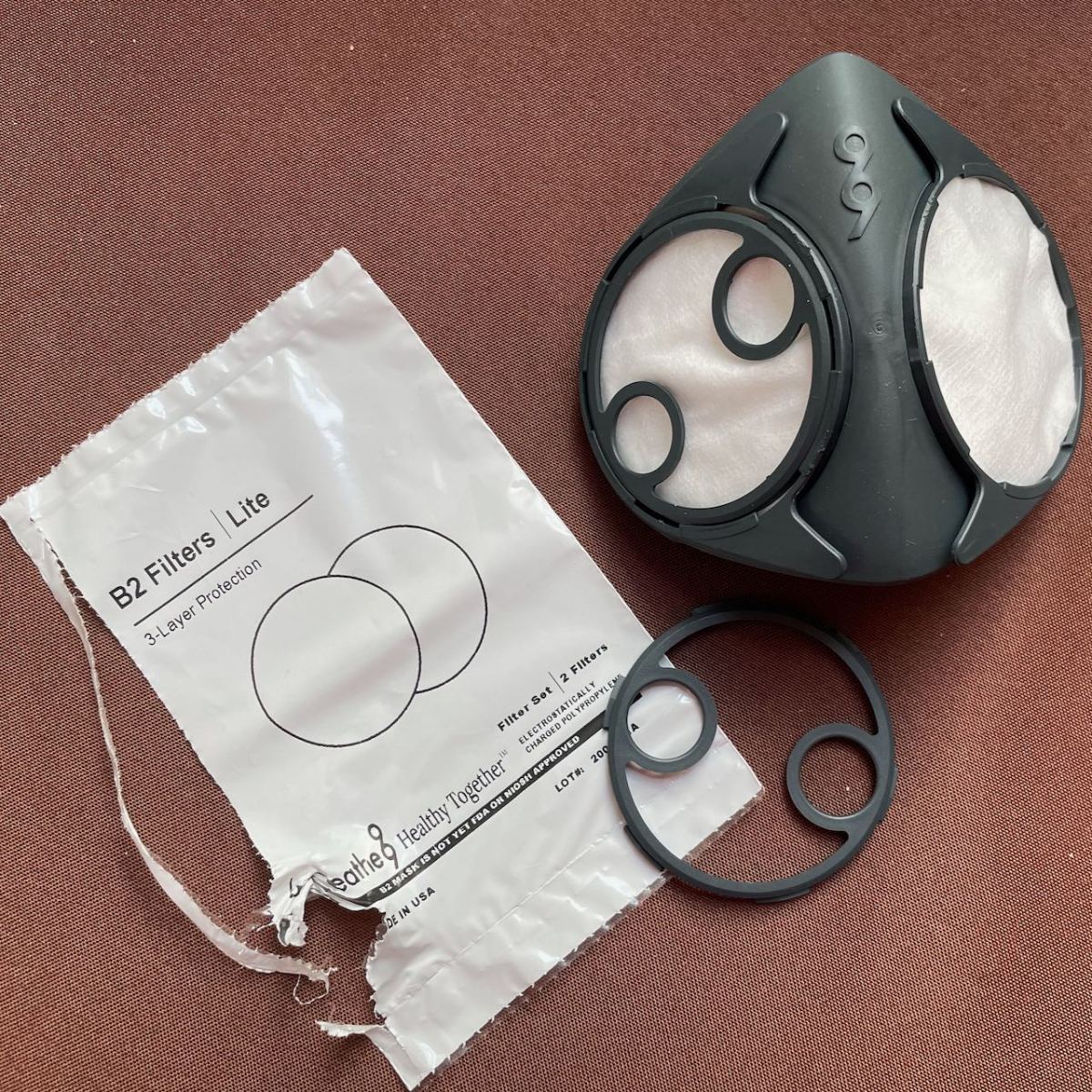 Ergonomic face piece with one filter cap on over a filter and the second filter installed but not yet capped