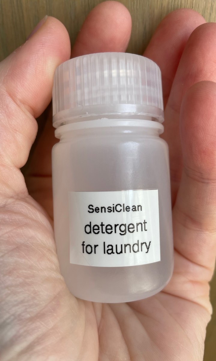Small bottle filled with laundry detergent held in palm of hand