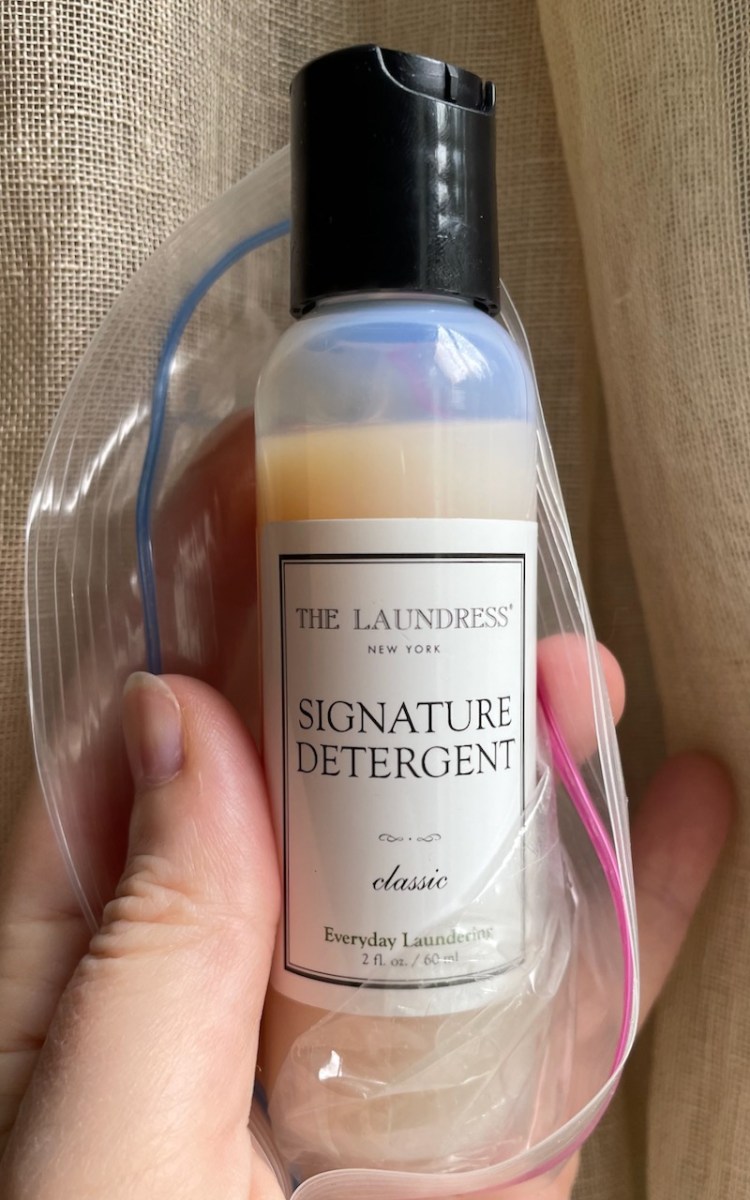2 oz Signature Detergent trial size laundry soap in Ziploc in a woman's hand