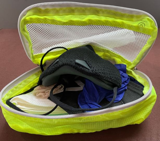 Neon yellow Uncharted zippered packing cube with B2 mask, several disposable masks, and a pair of gloves inside