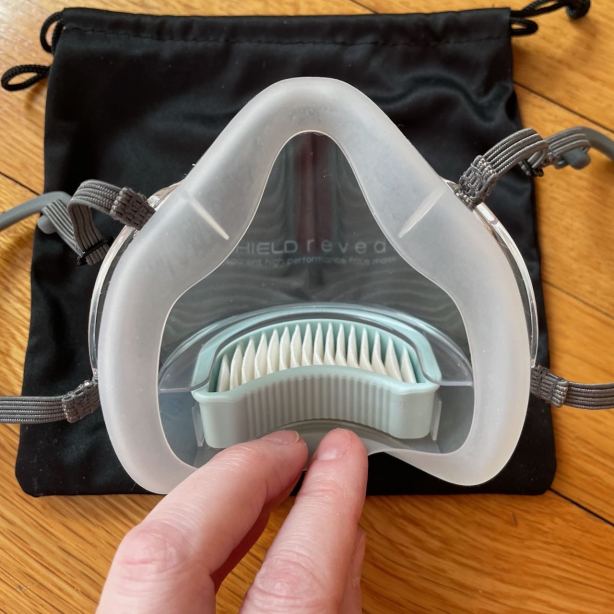 Fingers pull silicone gasket away from Reveal mask to show filter mounted in bottom slot