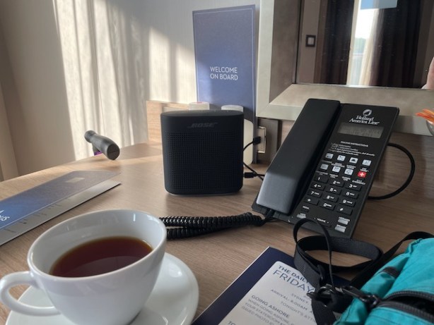 HAL's speaker charging by stateroom phone, room service menu, daily program, and a cup of tea