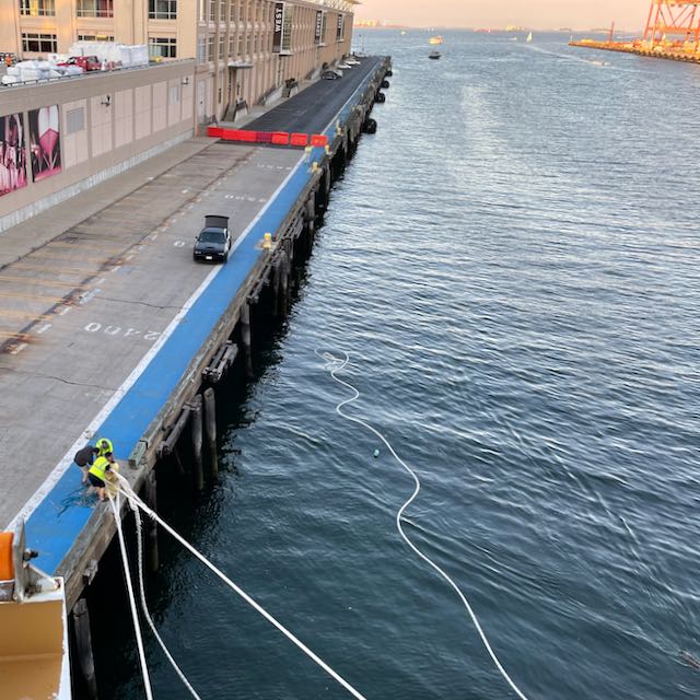 port employees releasing ropes holding Nieuw Statendam to dock