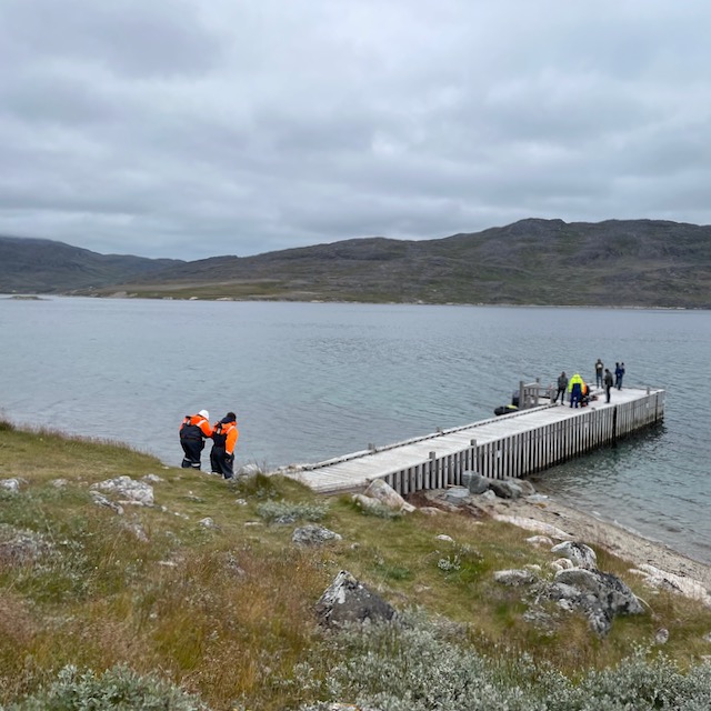 Person in orange leans on the guy next to her while negotiating steep slope to dock