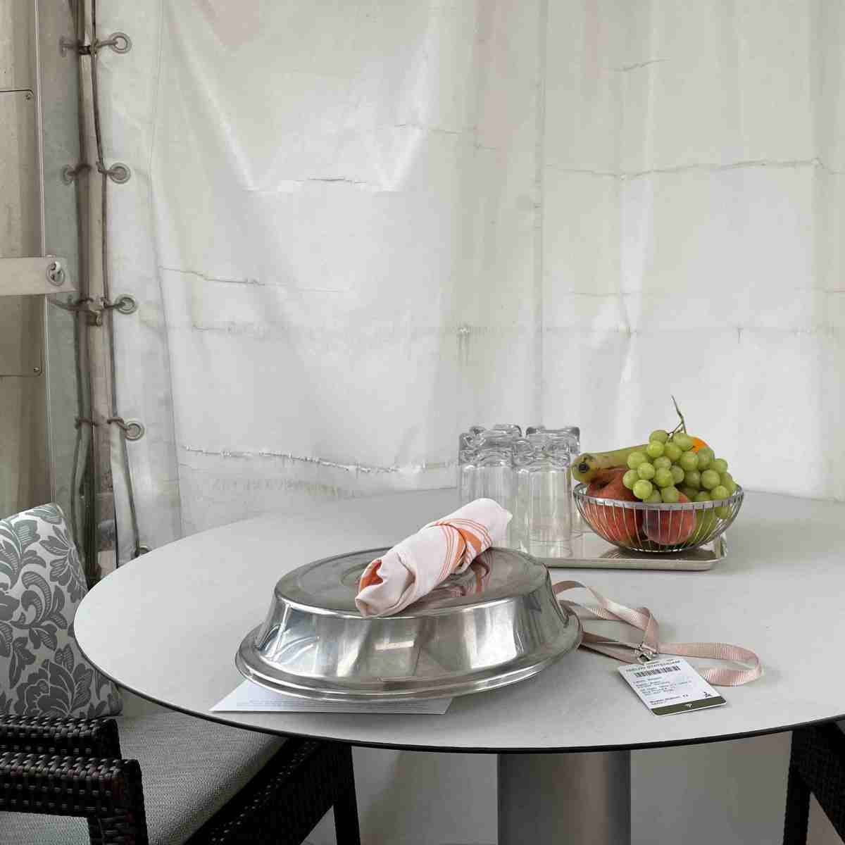 Cabana table with bowl of fresh fruit and meal under cloche as delivered from Lido buffet
