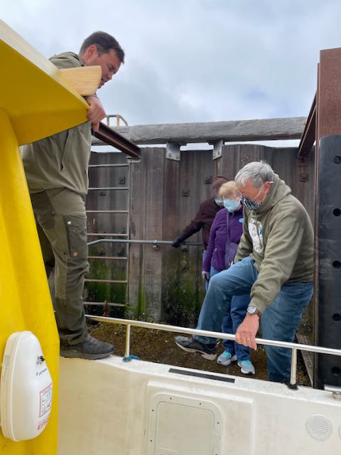 Toni watches as a man steps over high side of boat while holding ship's rail