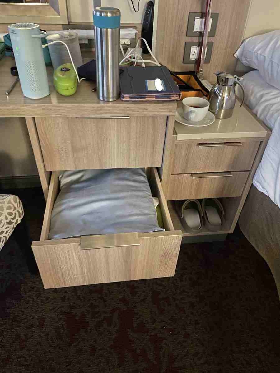 Cluttered desktop with charging devices, water bottle & teapot