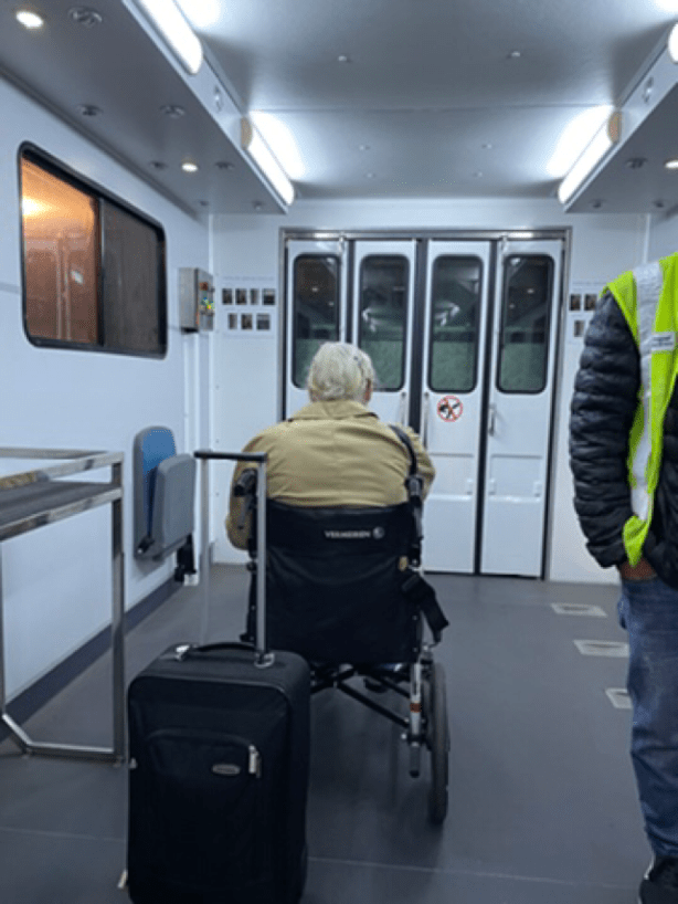 View of passenger in wheelchair inside lift used to lower people from plane